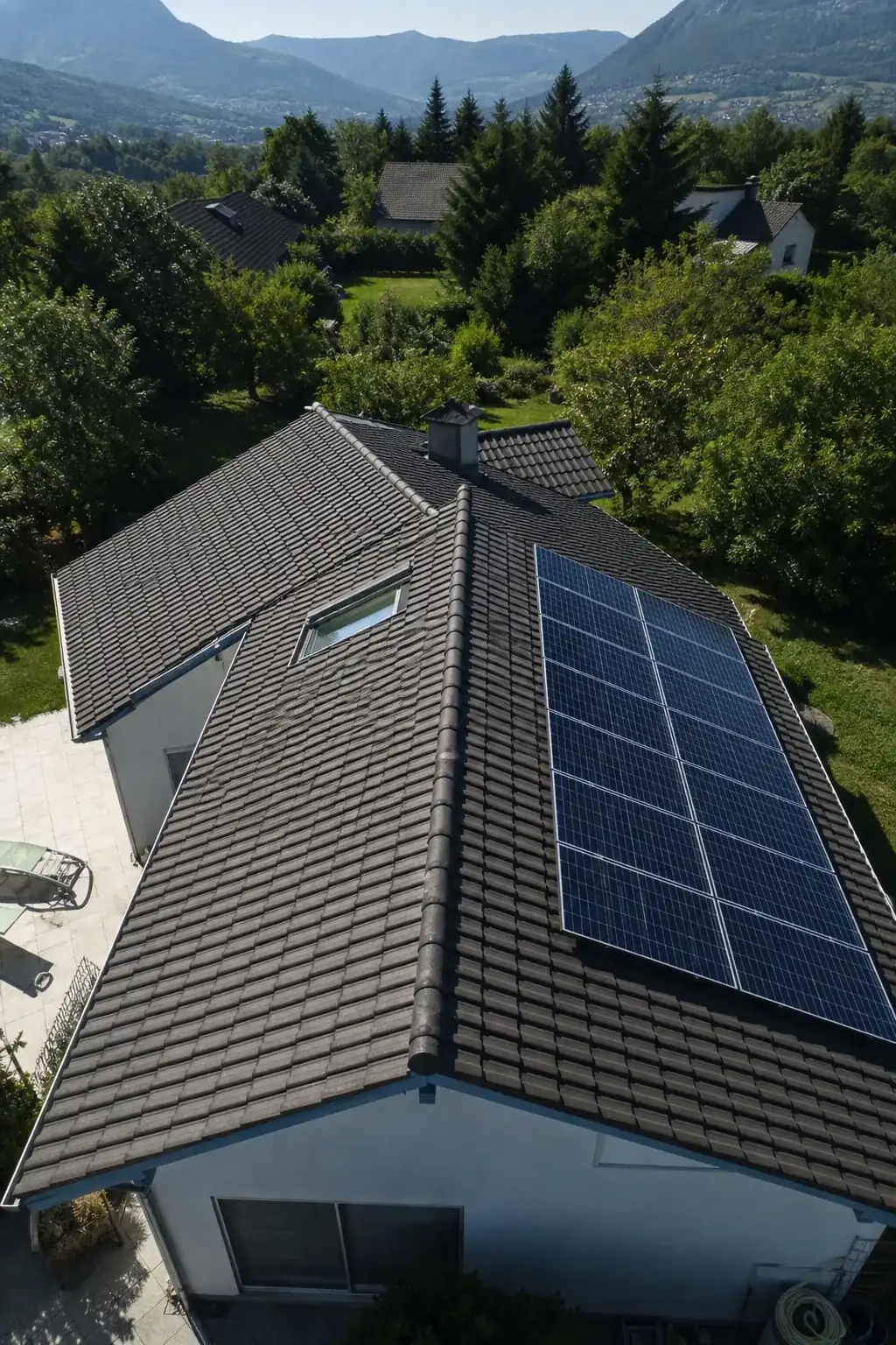 Vue en plongée d’une toiture dont le pan sud porte des panneaux solaires quand le pan nord est resté nu