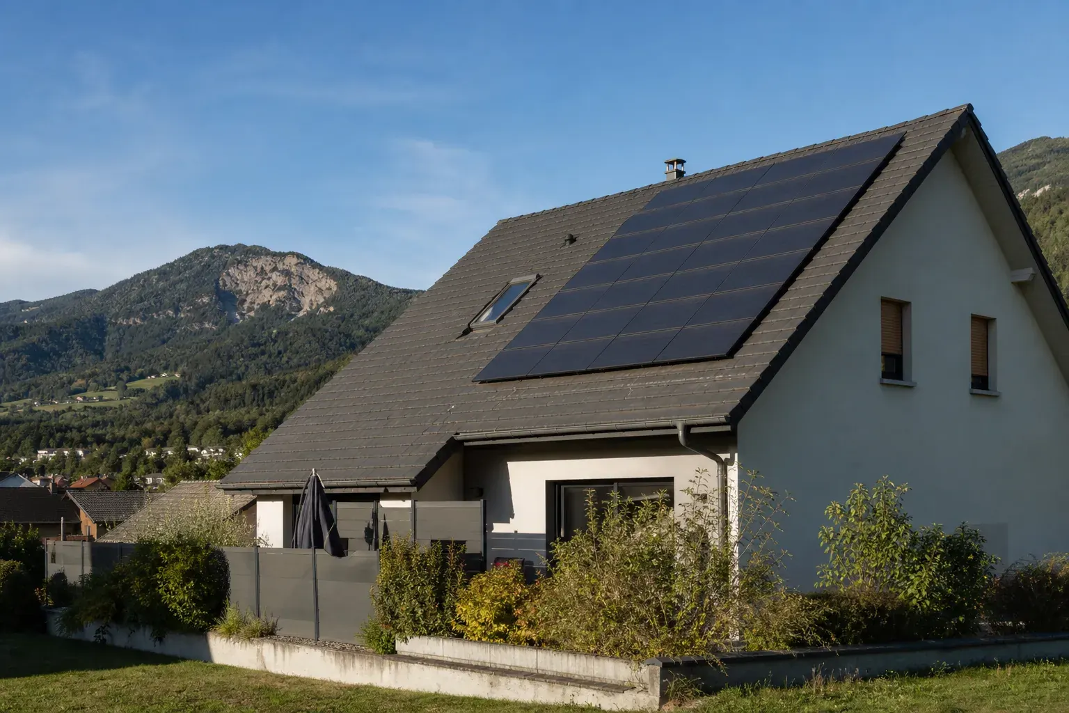 Maison individuelle de montagne dont le pan de toiture exposé au sud est entièrement couvert de panneaux photovoltaïques